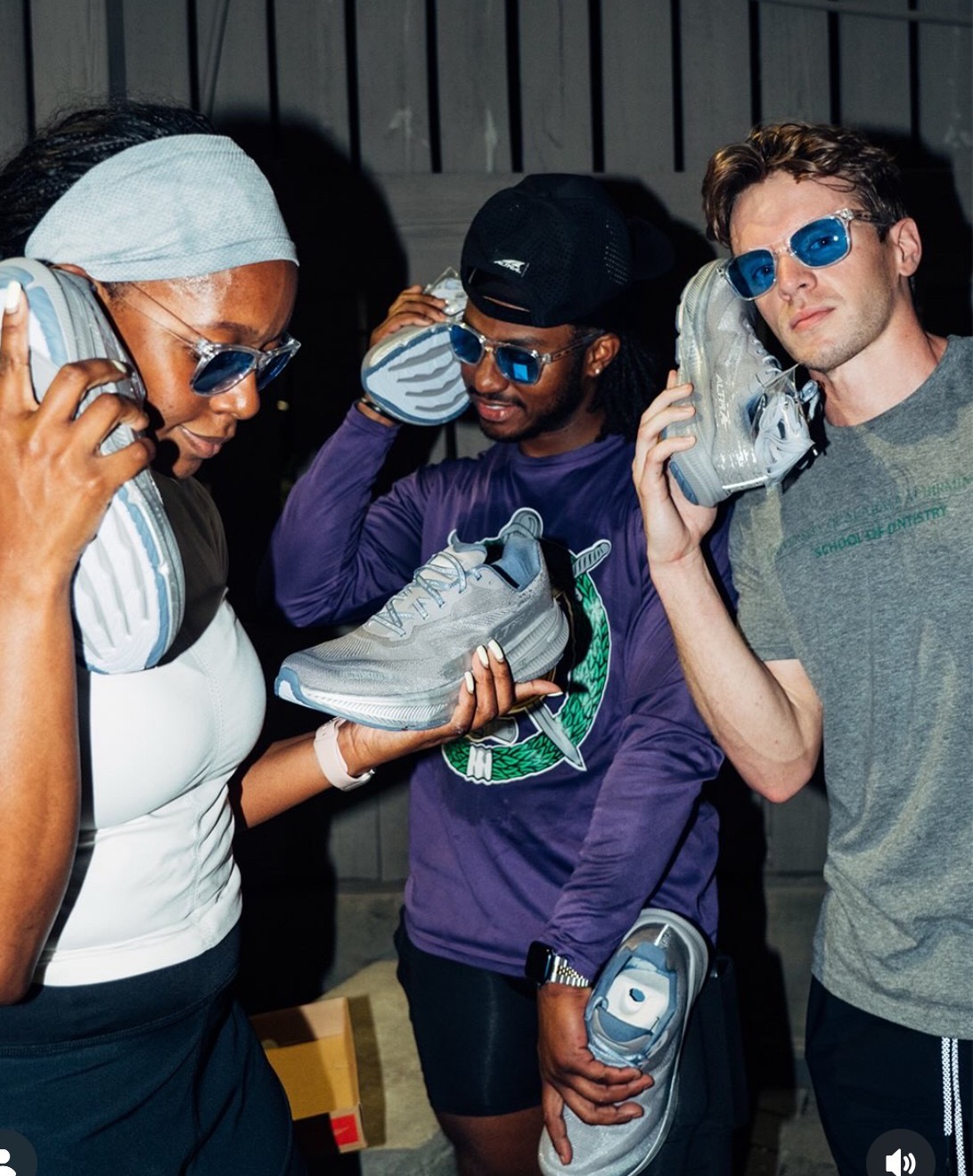 Three runners holding new running shoes up to their ears